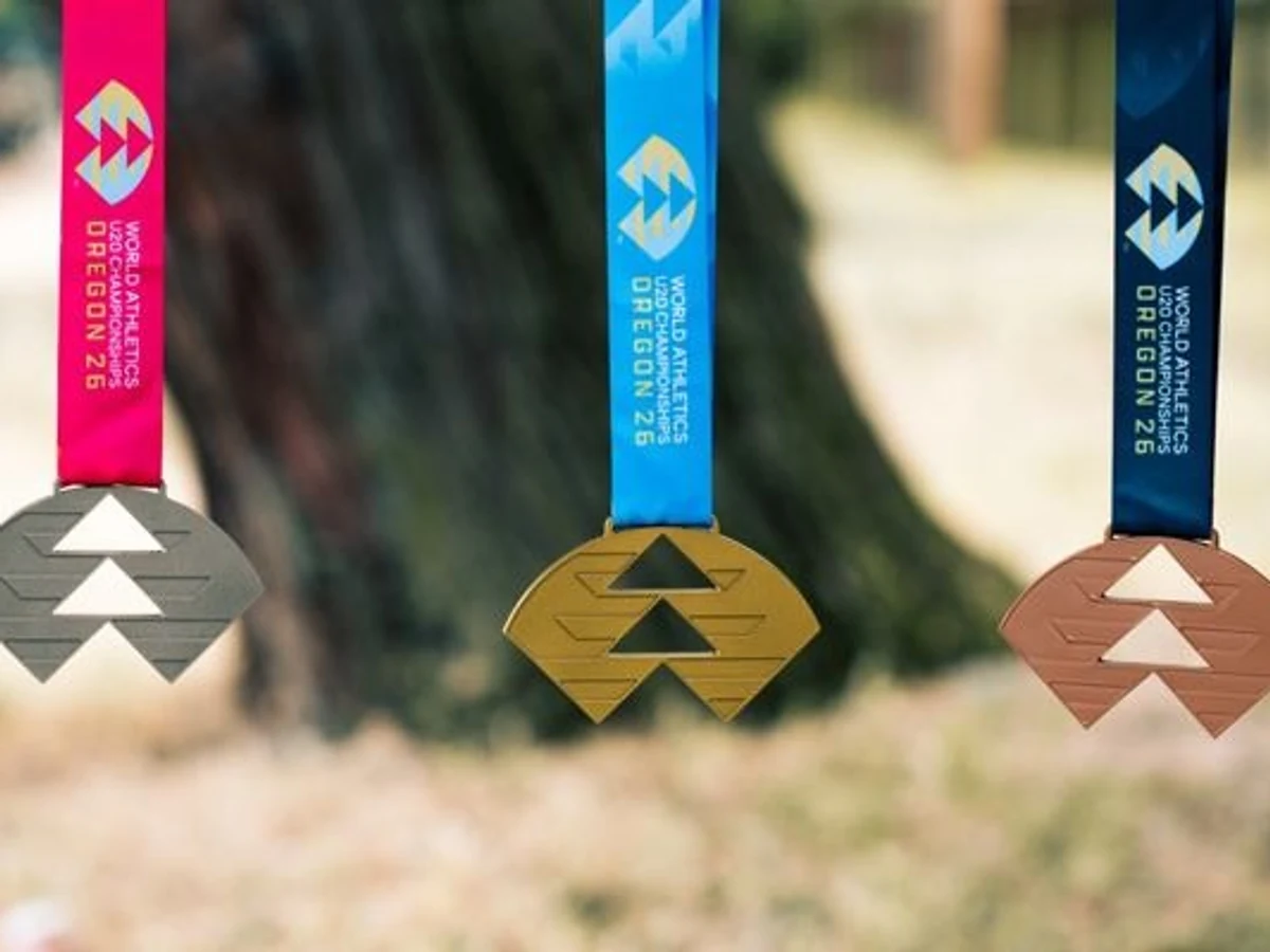 Silver, gold and bronze Oregon 26 medals hang from pink, blue and dark-blue ribbons outdoors.